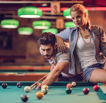 Young couple playing snooker in a pool hall.